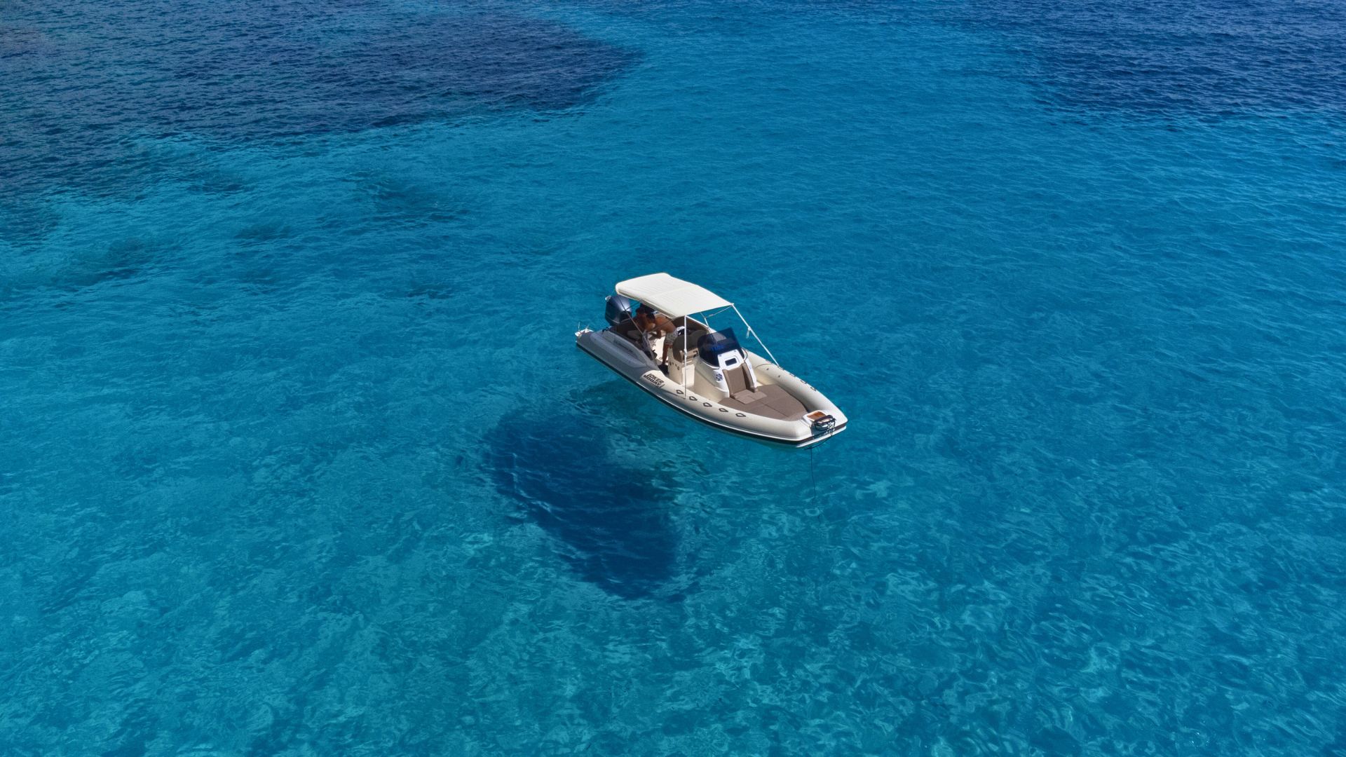 Dinghy sailing in the crystal clear waters of Cala Biriala